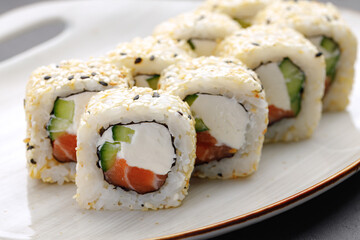 Sushi roll with salmon, philadelphia cheese and sesame on plate close up
