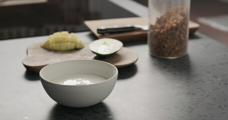 Obraz na płótnie Canvas making granola with mango in white bowl on kitchen