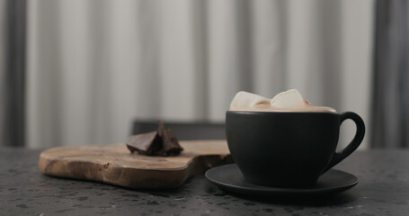 marshmallow in cup with hot chocolate on concrete countertop