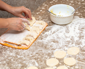 The girl sculpts dumplings from dough.