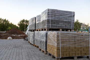 stacks of pallets with bricks on the street for the repair of the pedestrian road