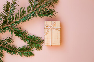 Gift yellow box with ribbon and fir branch on pink background, top view. Christmas composition. Selective focus