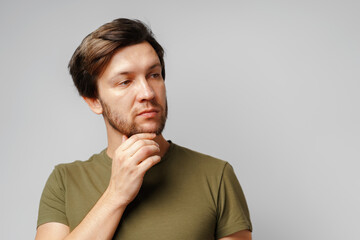 Portrait of a serious pensive young man against grey background