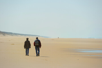 Fototapeta na wymiar Couple walking on the sand on a ocean beach