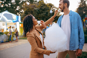 Love couple eating cotton candy in amusement park