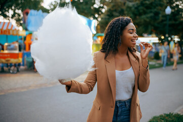 Cheerful woman with cotton candy in amusement park