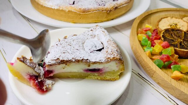 Eat a spoonful of cheesecake. A piece of cake on a white saucer. Plum cake for the holiday.