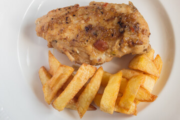 Top view of a plate of chicken food with vegetables and potatoes on a wooden table. Cooked dishes.