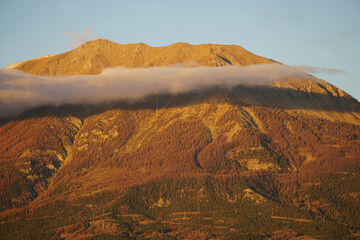 sun setting on the peak with a wisp of a cloud in the French Alps