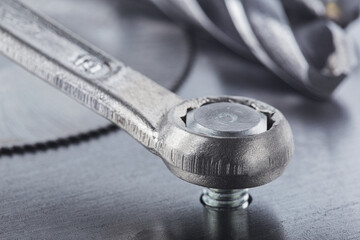 Wrench tightens bolt in steel billet. Spanner, bolt, screw and nuts.