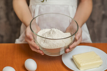 Girl holding a cup of flour in the kitchen. Homemade baking.