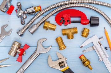 Necessary set of tools and spare parts for plumbers on blue wooden background