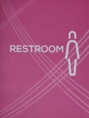 female restroom sign on light pink background.