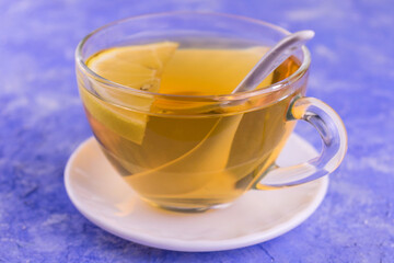 
Tea with lemon in a transparent cup on a blue background.
Close-up.