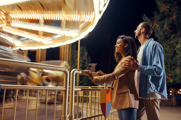Couple at the carousel in motion, amusement park