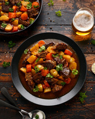 Beef Stew with carrot and baby potato in black plate on wooden table