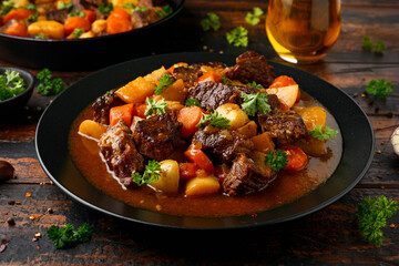Beef Stew with carrot and baby potato in black plate on wooden table