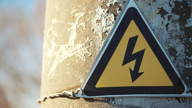 electricity safety sign on the pole next to the transformer. yellow sign lightning danger high voltage concept electricity. triangle high electricity. safe working with electricity energy