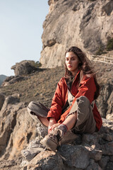 Naklejka na ściany i meble Young woman sitting on the cliff along the Golitsyn Hiking trail in the village of Novy Svet, Crimea. Clear Sunny day. Hiking, traveling, Freedom, Lifestyle concept.