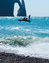 People jumping from floating pontoon at sea, Atlantic ocean. La Porte d'Aval natural rock arch...