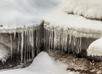 Icicles and frost on a snow-covered frozen river