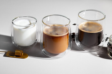 Glass cups of coffee and milk on white table