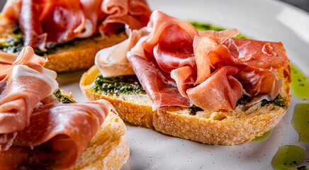 Bruschetta with prosciutto and pesto sauce on plate