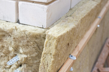 Insulation of a brick wall with mineral glass wool before cold winter season. Boulding new warm house