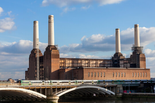 Battersea Power Station in London England UK a coal fired building built in 1935 on the River Thames with a passing railway train showing public transport infrastructure, stock photo image
