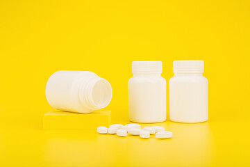 Colorful still life with medication bottles and spilled pills on yellow background. The concept of pharmacy and health care or vitamins for kids
