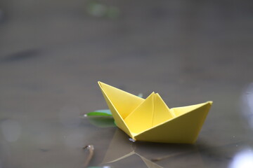 Yellow paper boat on muddy water-floating 