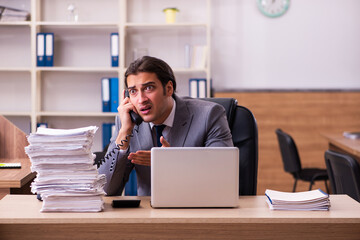 Young male employee unhappy with excessive work in the office