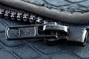 A macro shot of a open, plastic zipper in a modern blue garment.