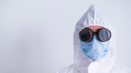 Portrait of a woman in a protective suit wearing a mask with glasses on a white background. A female doctor in uniform during a pandemic.