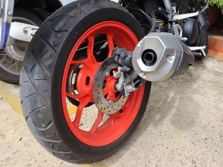 Close-up of the rear wheel of a big bike, red rims Modern exhaust pipe