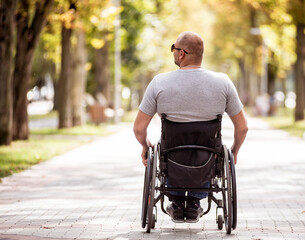 Handicapped man in wheelchair walk at the park alley