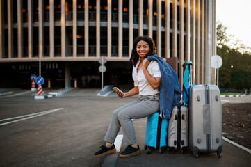 Fototapeta na wymiar Woman sitting on suitcase, entrance to car parking