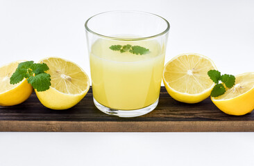 Fresh lemon fruit juice in a glass, lemon balm leaves. White background. Isolate.