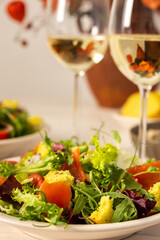 Light breakfast or dinner, mix salad with salmon and different seeds and two glasses of white wine, plate with salad and cornbread close up