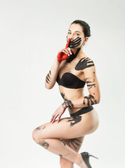 Fototapeta na wymiar a woman in underwear smeared with black paint on a white background