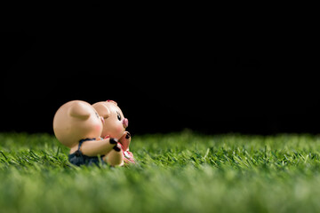A toy pig on a grassy field against a black background