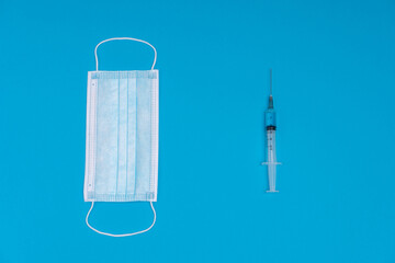 Fototapeta na wymiar 2021 logo made from a medical mask and a syringe with a vaccine. As a symbol of the pandemic and the release of the drug in 2021. Blue background