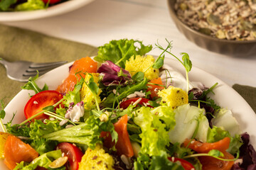 Light breakfast or dinner, mix salad with salmon and different seeds, plate with salad and cornbread close up