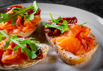 bruschetta with salmon,cherry tomatoes,fresh arugula and cream cheese on plate