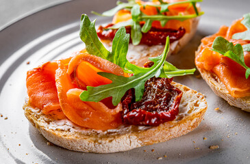 bruschetta with salmon,cherry tomatoes,fresh arugula and cream cheese on plate