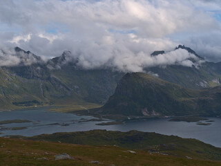 Beautiful panoramic view of the rugged mountains of Flakstad&oslash;ya island including peak of Volandstinden and fjord Selfjorden viewed from the top of Ryten, Moskenes&oslash;ya, Lofoten, Norway with cloudy sky.