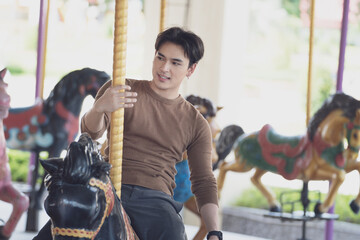 Fototapeta na wymiar couple asian man and woman dating and riding on horse at Carousel amusement park. Concept happy and lovely life of teenager.