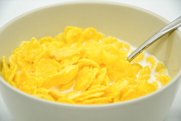 Close-up of cornflakes with milk-soaked in deep bowl with spoon. Healthy nutritious diet food for adults and children. Popular breakfast all over the world.