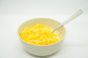 Close-up of cornflakes with milk-soaked in deep bowl with spoon. Healthy nutritious diet food for adults and children. Popular breakfast all over the world.