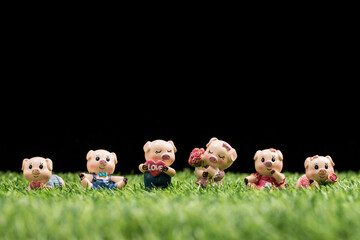 A toy pig on a grassy field against a black background